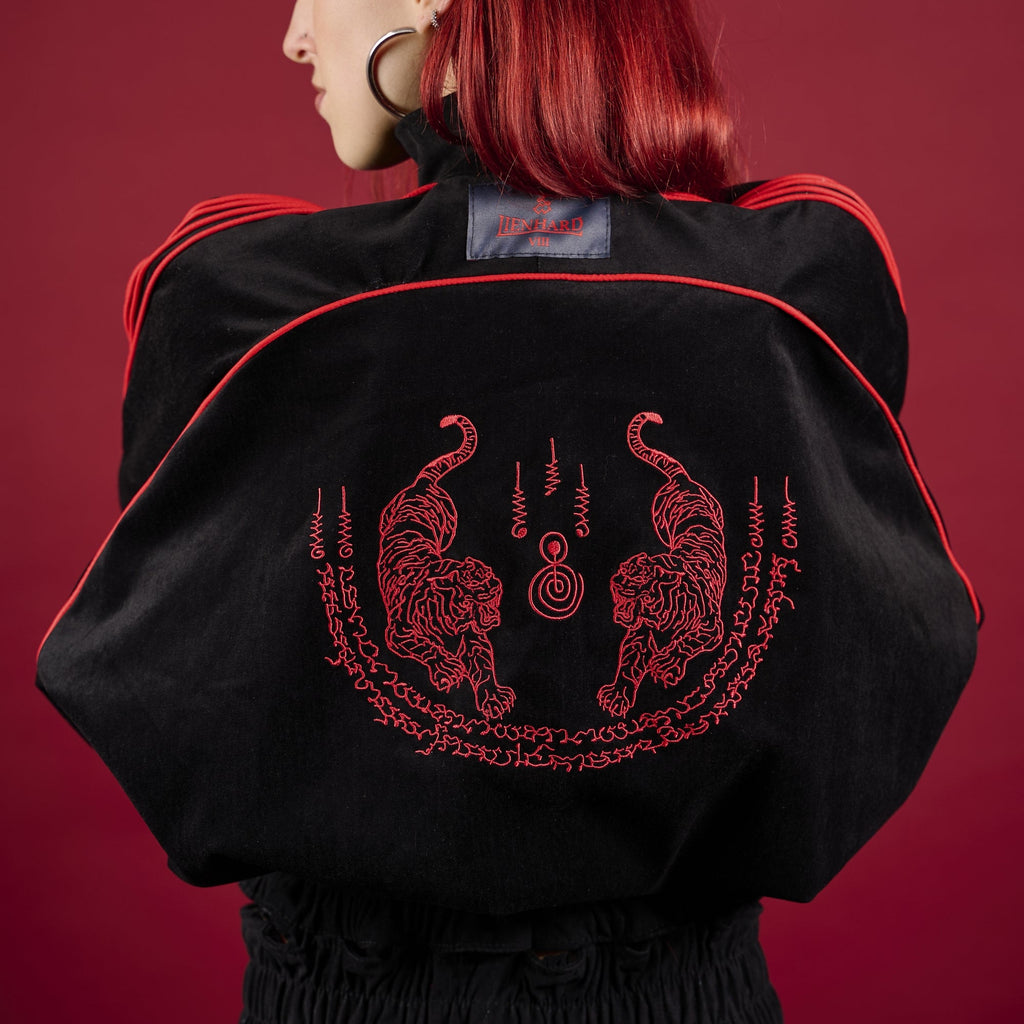 Person wearing a black jacket with red designs and text on a red background