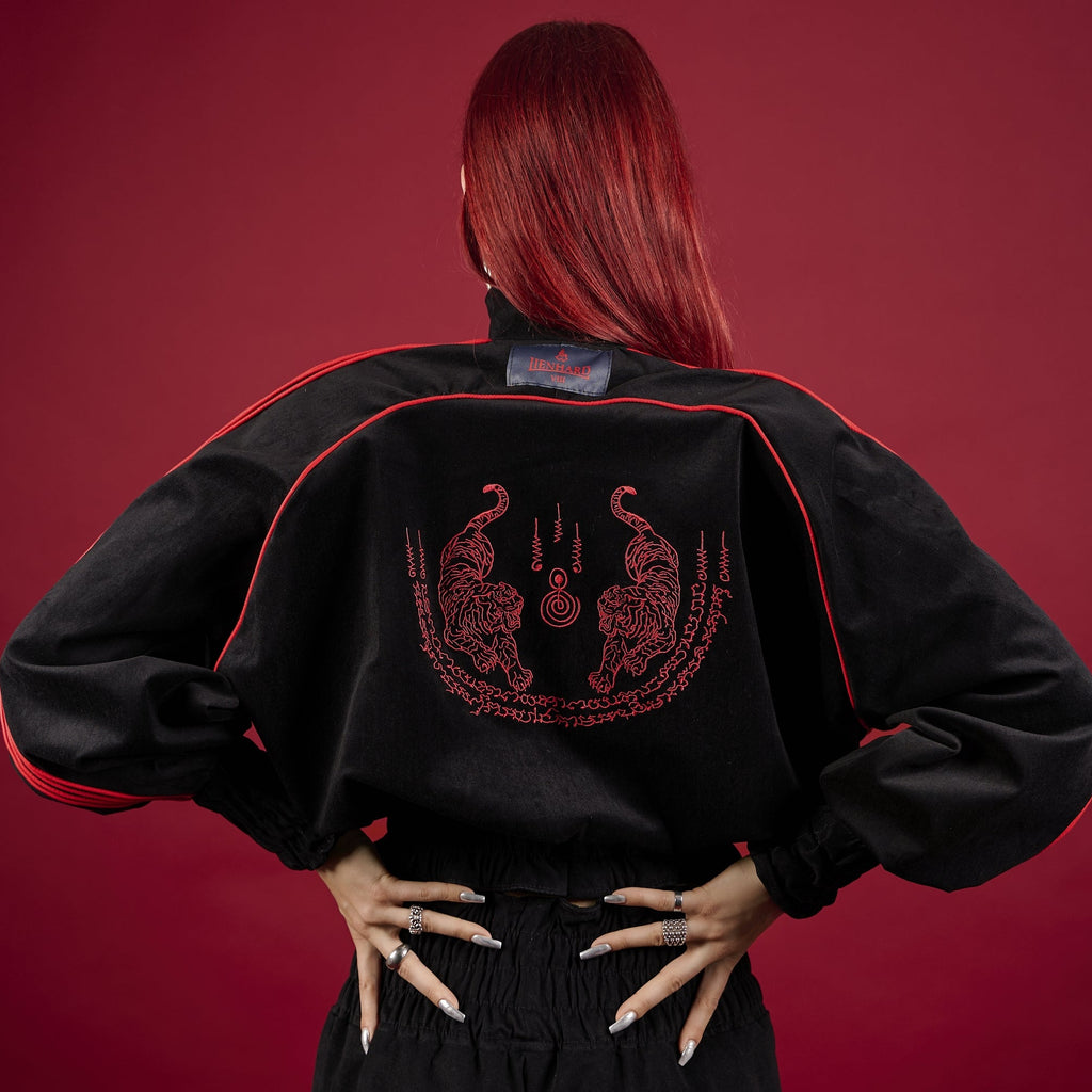 Person wearing a black jacket with red embroidery on a red background Muay Thai Sak Yant Clothing Tracksuit Muay Thai Tracksuit