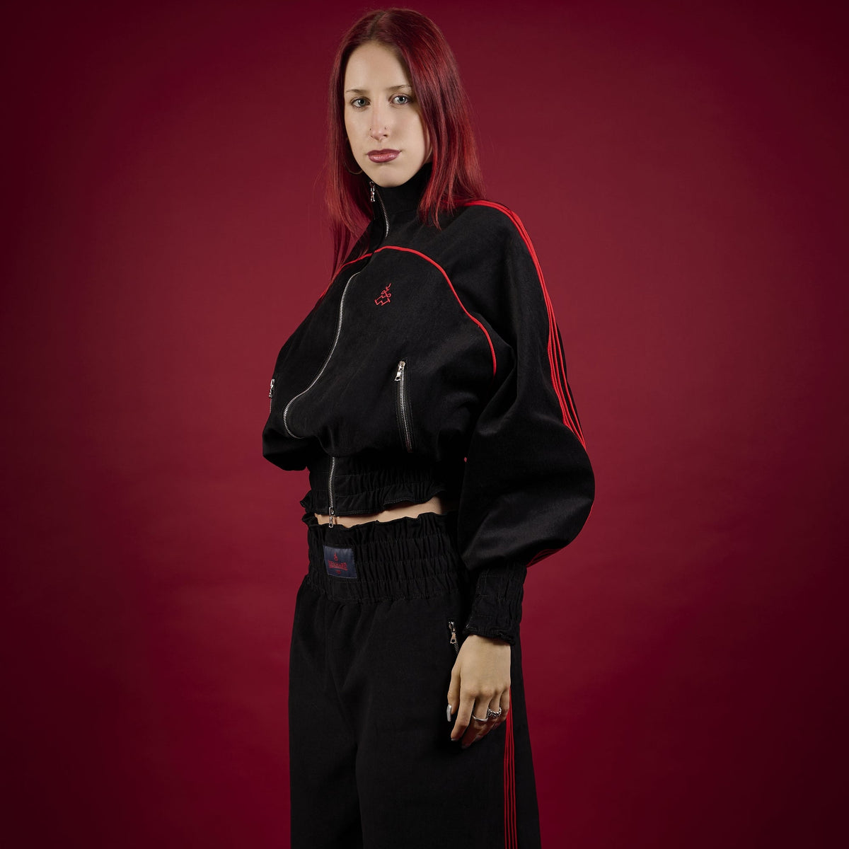 Person wearing a black outfit with red accents on a red background Lienhard VIII Muay Thai Tracksuit Women